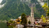 Charming lakeside church spire with a dramatic mountain backdrop in Hallstatt, Austria