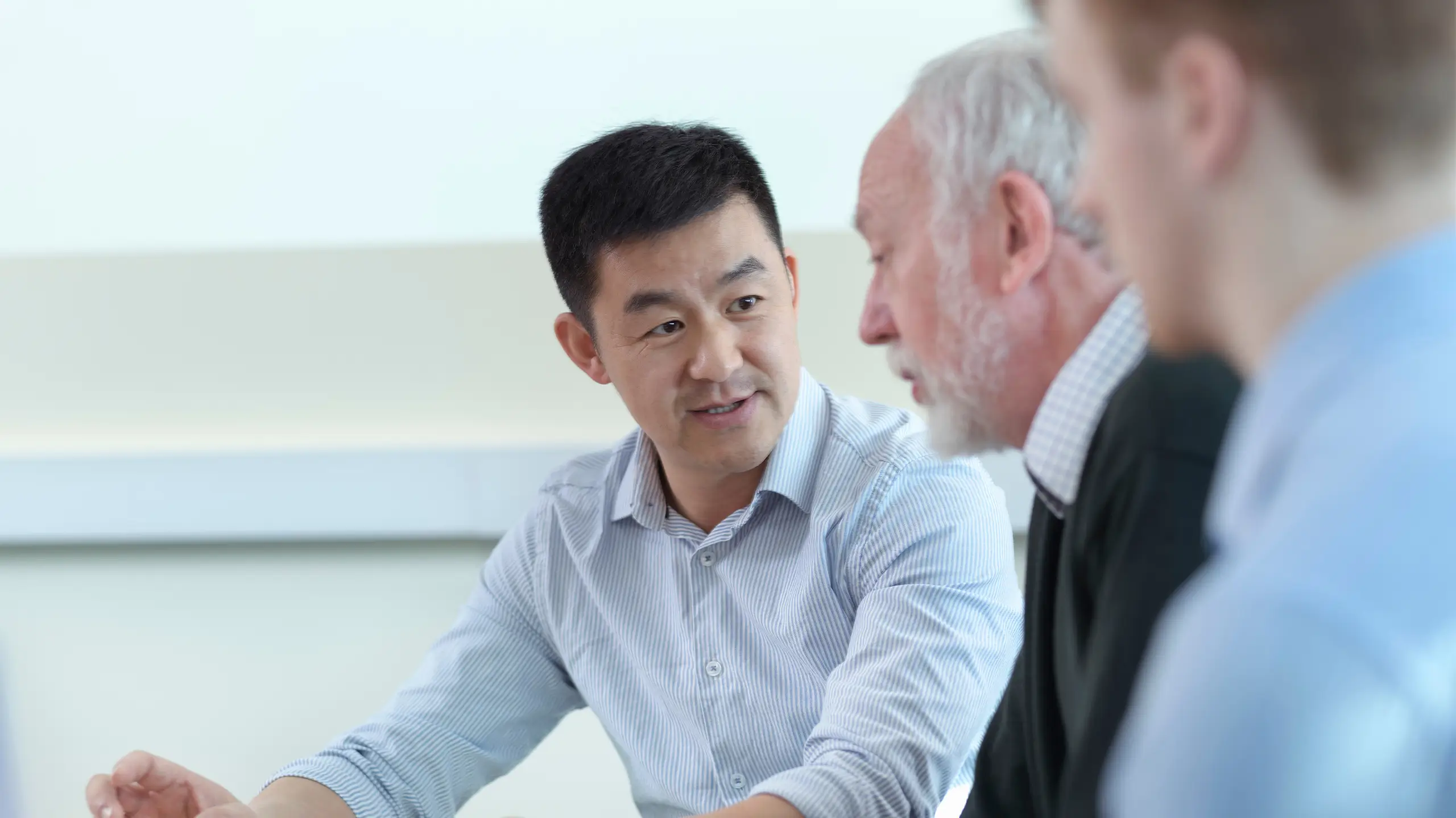 Younger and older scientists discussing pharmaceutical science project in meeting room